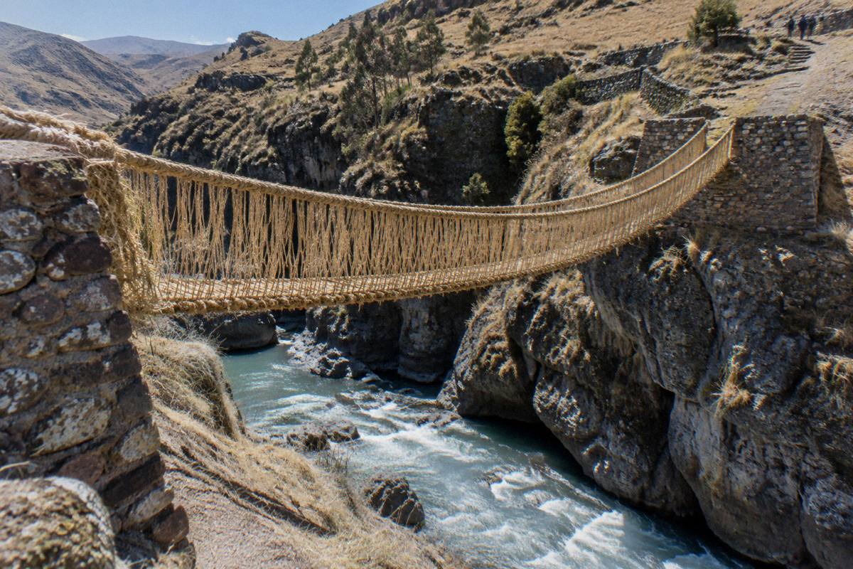 The woven grass rope suspension bridge spanning a rocky gorge with a fast river, stone abutments, nobody on it, Q'eswachaka Bridge