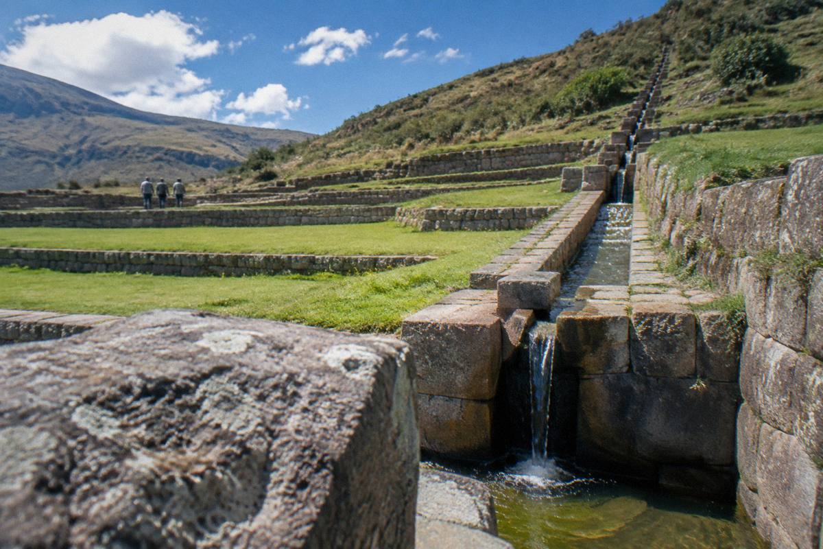 Long green stone-walled terraces at Tipon with a water channel climbing a hillside