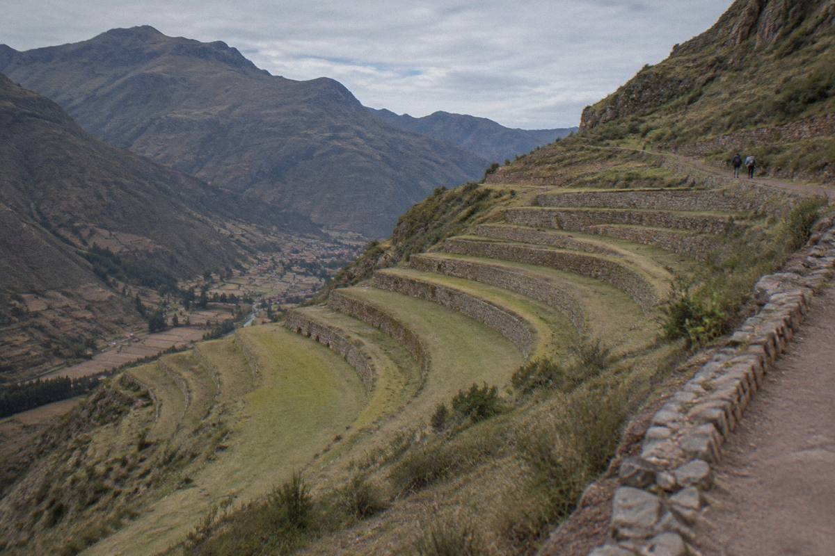 Curved Inca farming terraces on a steep mountainside above the Pisac valley, a few distant visitors on a path, Pisac Archaeological Park