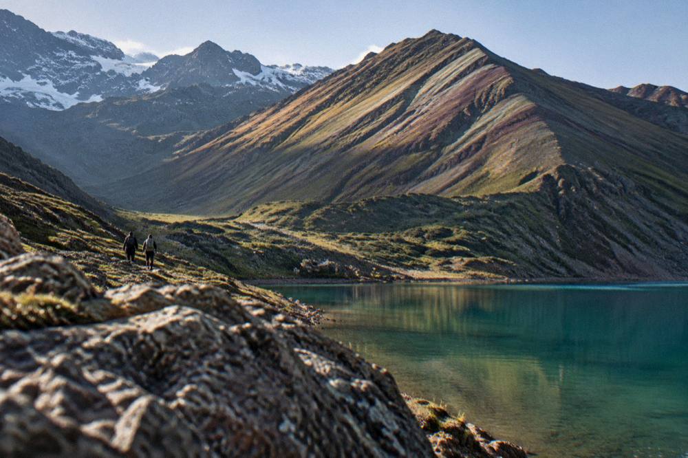 A striped mineral ridge rising above a green highland valley