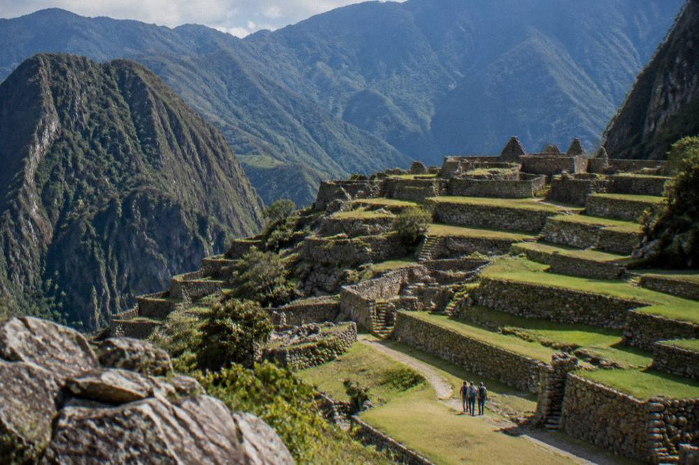 A wide valley with agricultural terraces cut into a hillside below mountains