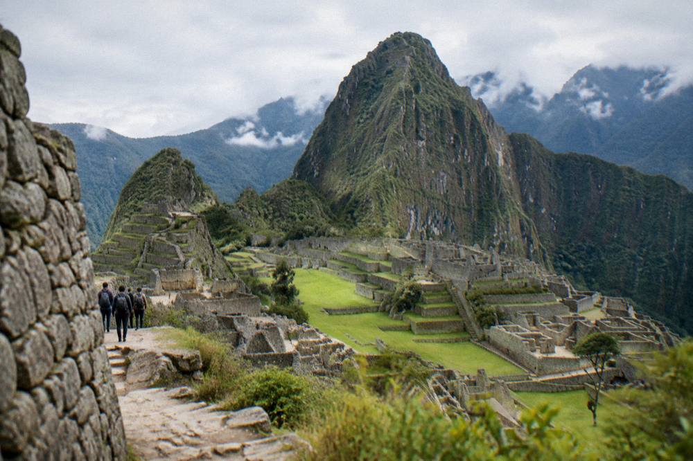 The stone walls and green terraces of Machu Picchu under a wide afternoon sky