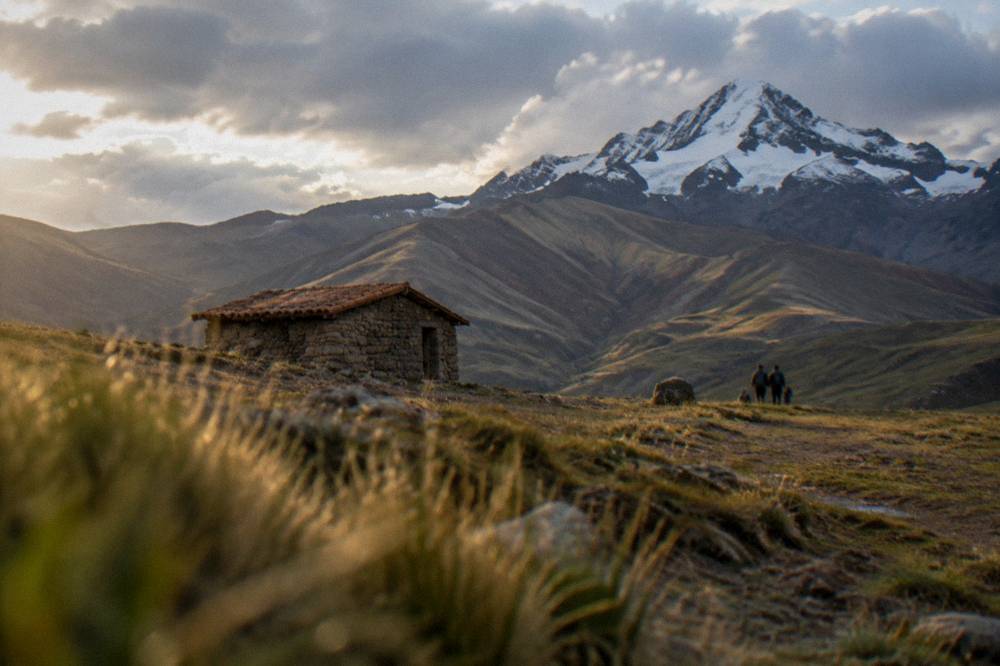 A small stone shelter on a high plain with a snow-capped peak behind it