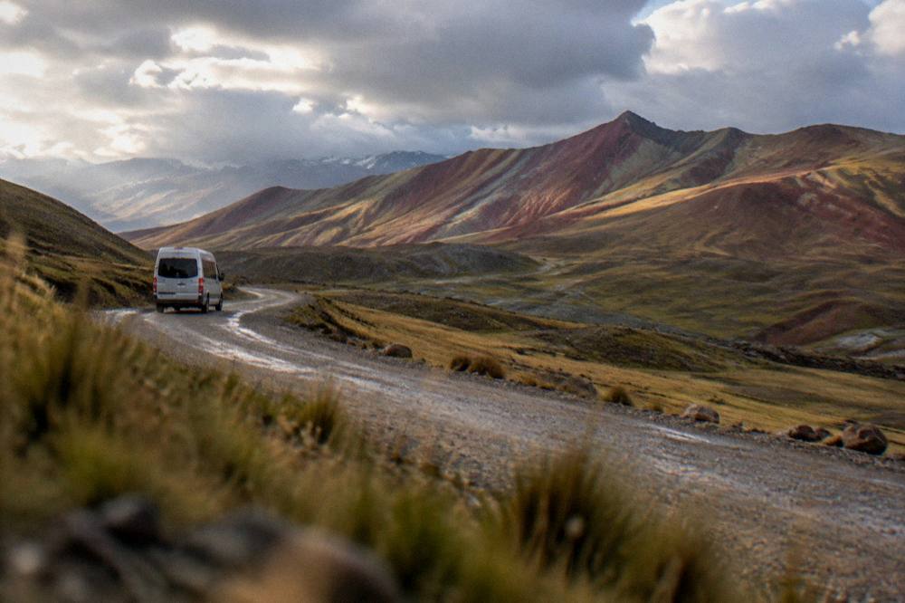 A tour van on a gravel road winding through wide open highland country