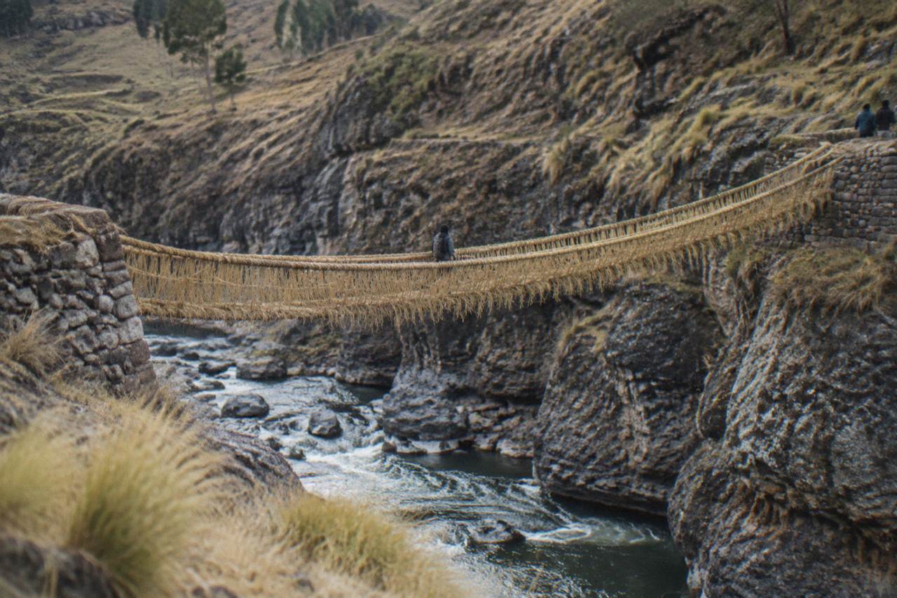 A woven grass rope bridge spanning a river gorge in the high Andes of Peru