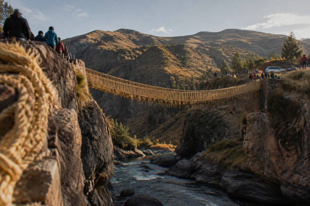 Festival crowds and woven banners beside a river gorge in the Peruvian Andes