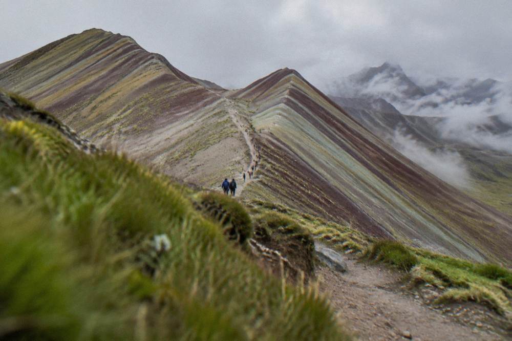 Two striped ridgelines in pale sunlight with a walking path climbing between them