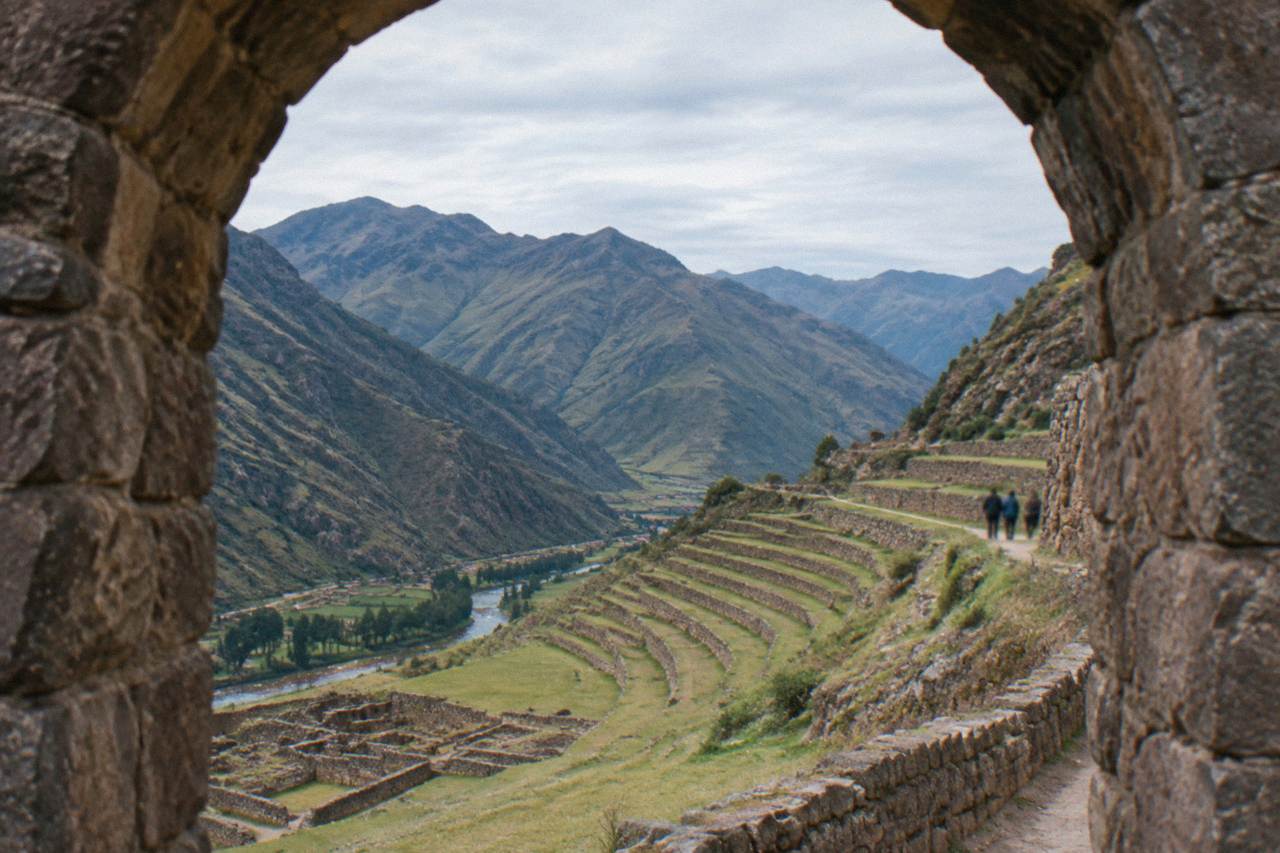 Terraced fields on a hillside above the Urubamba river with Andean peaks in the distance