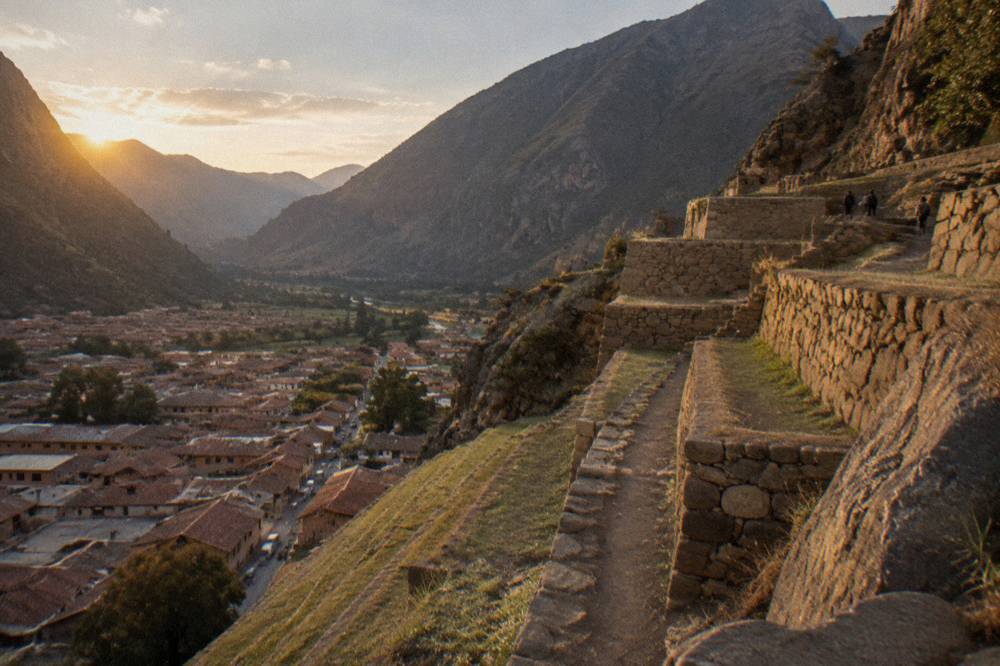 Steep stone terraces rising above the red tile roofs of Ollantaytambo
