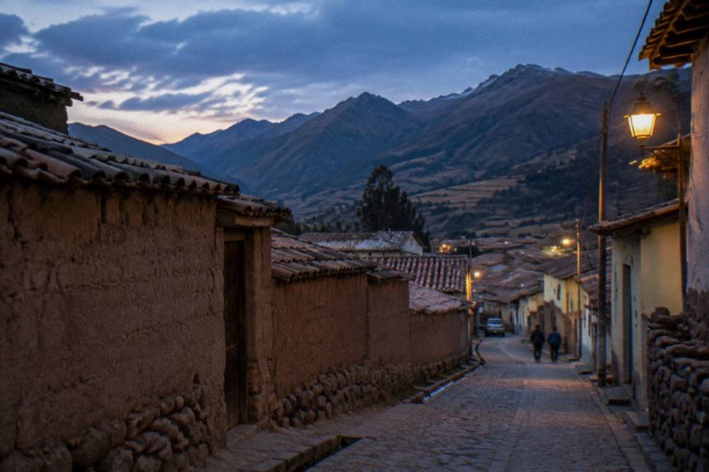 A highland village street with adobe walls and mountains rising behind the rooftops