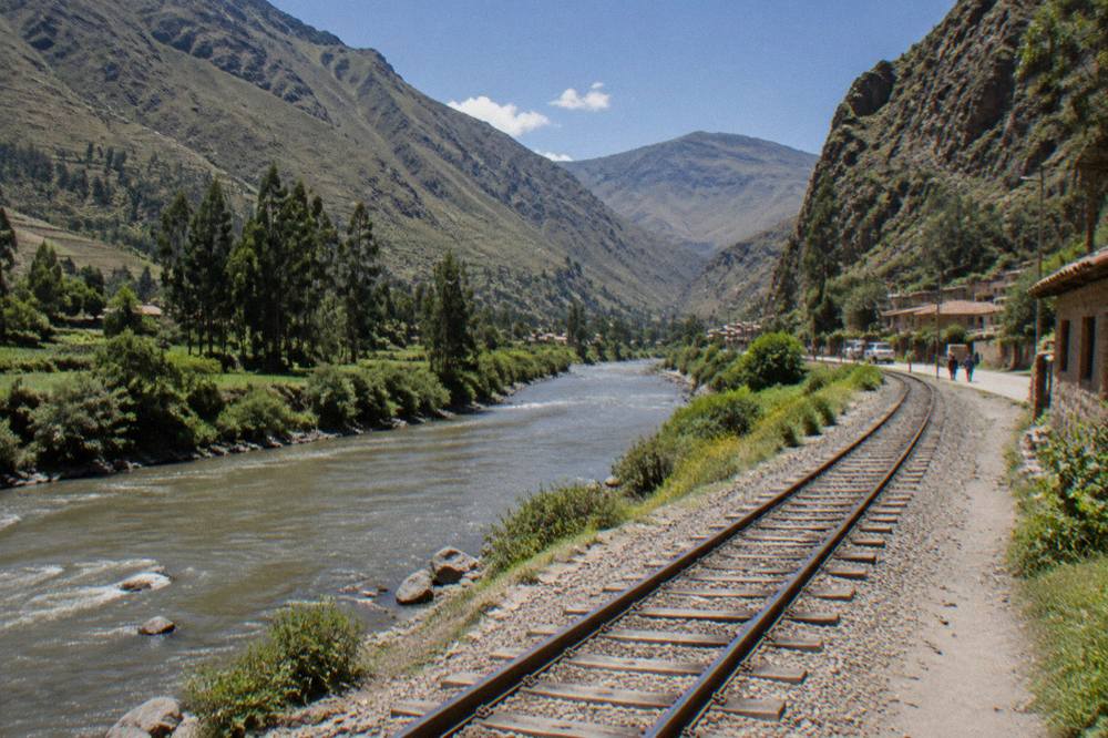 Railway tracks following a river through a green Andean valley