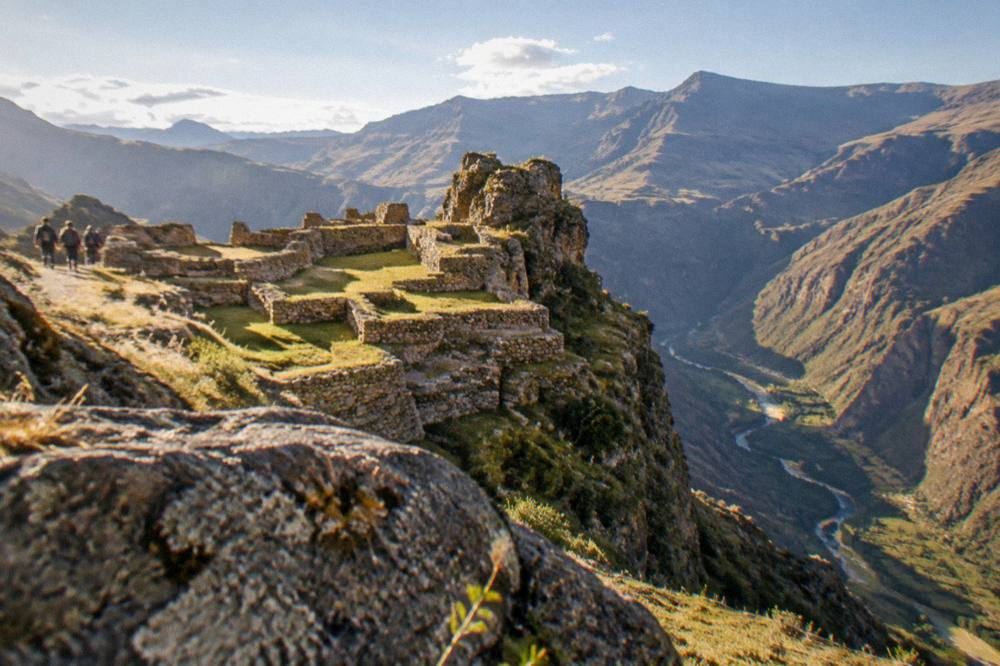 Golden morning light over layered Andean ridges with a river visible in a deep valley below