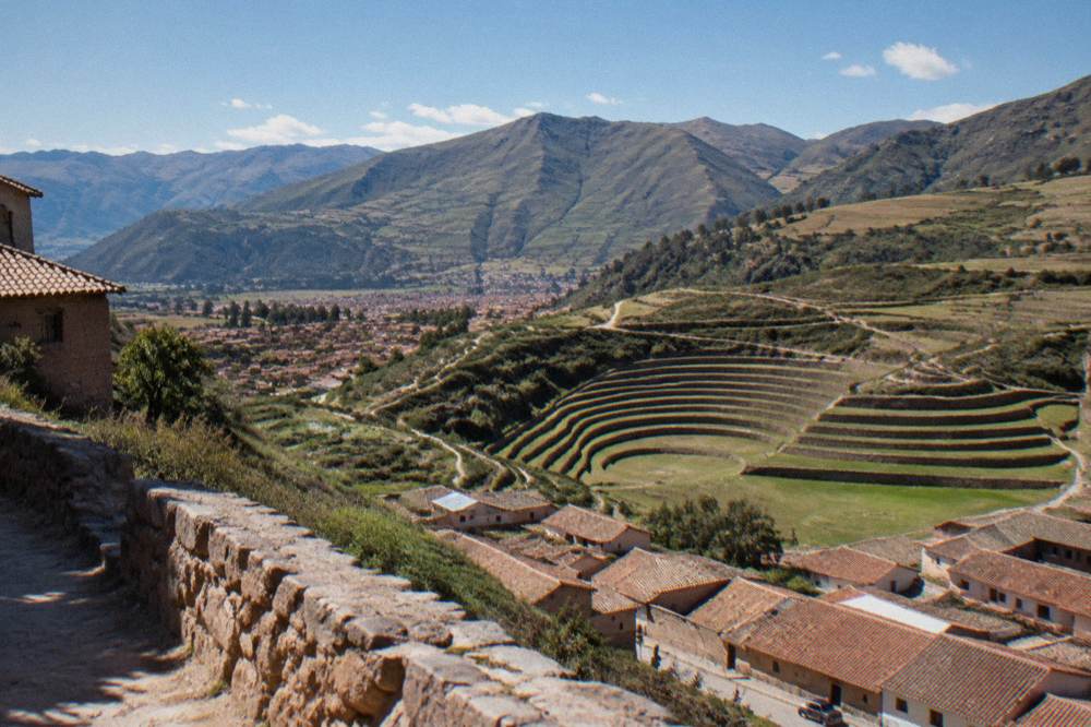 A clear dry-season morning over Cusco rooftops with green valley hills behind