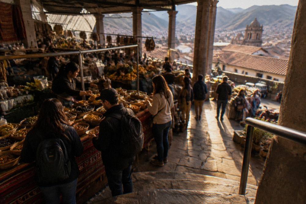 Visitors sampling food at a busy indoor market stall in Cusco