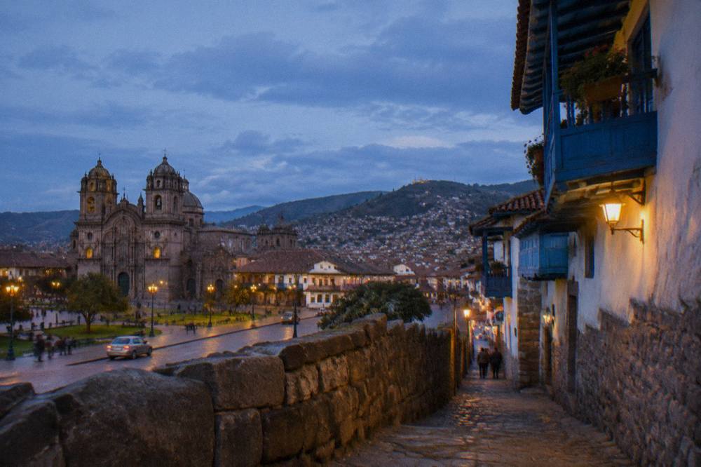 A stone alleyway in San Blas with blue balconies and a hillside view
