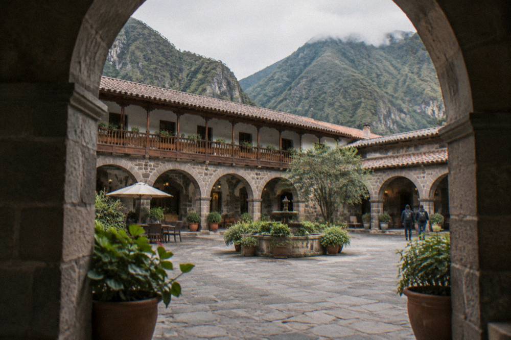 A hotel courtyard in Cusco with stone arches and potted plants