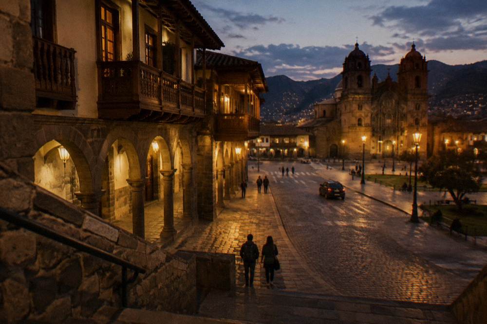 Colonial arcades and wooden balconies around a lit plaza at dusk in the historic centre