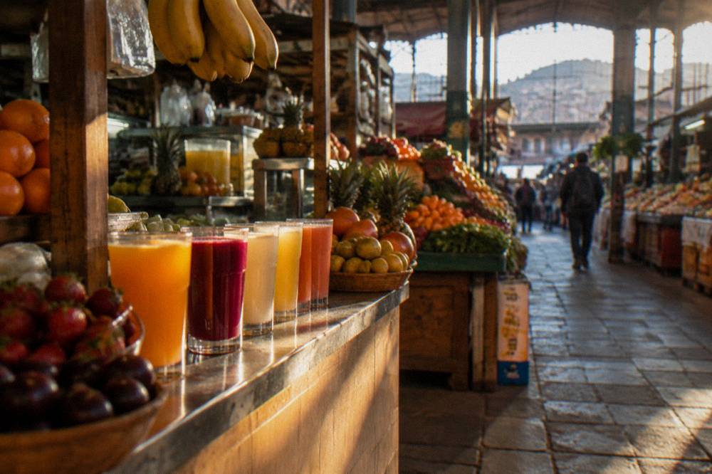 Glasses of fresh fruit juice and produce displays inside an indoor Andean market