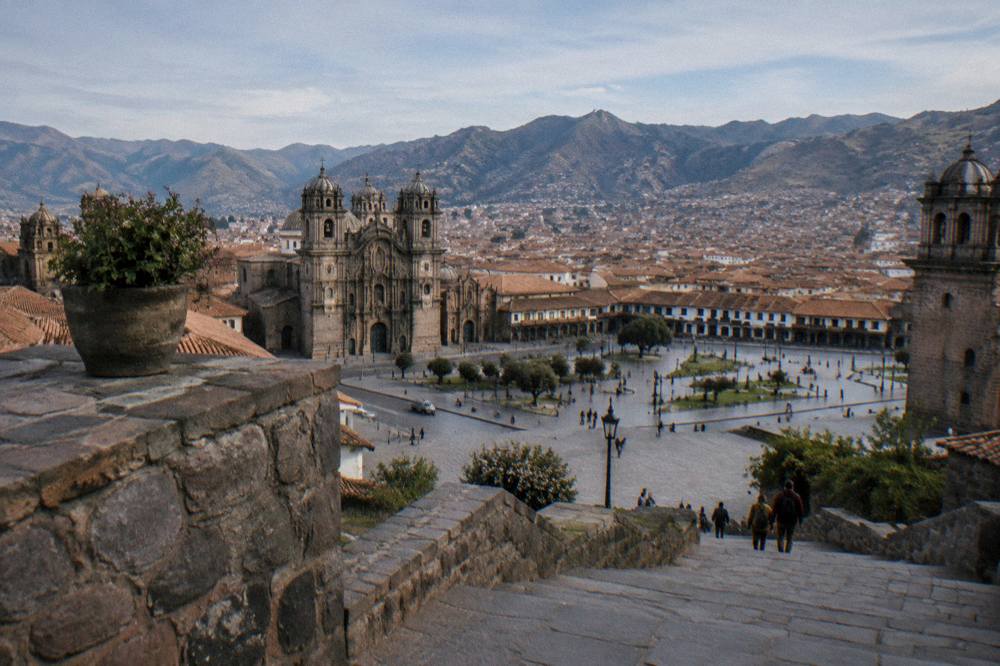 A stone terrace overlooking the red-tiled rooftops of Cusco under a clear sky