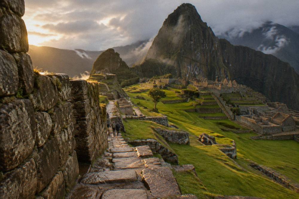 Inca stone wall with green grass after rain under a grey sky