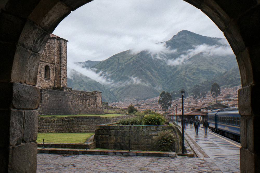 Train at a small Andean station platform with mountains behind