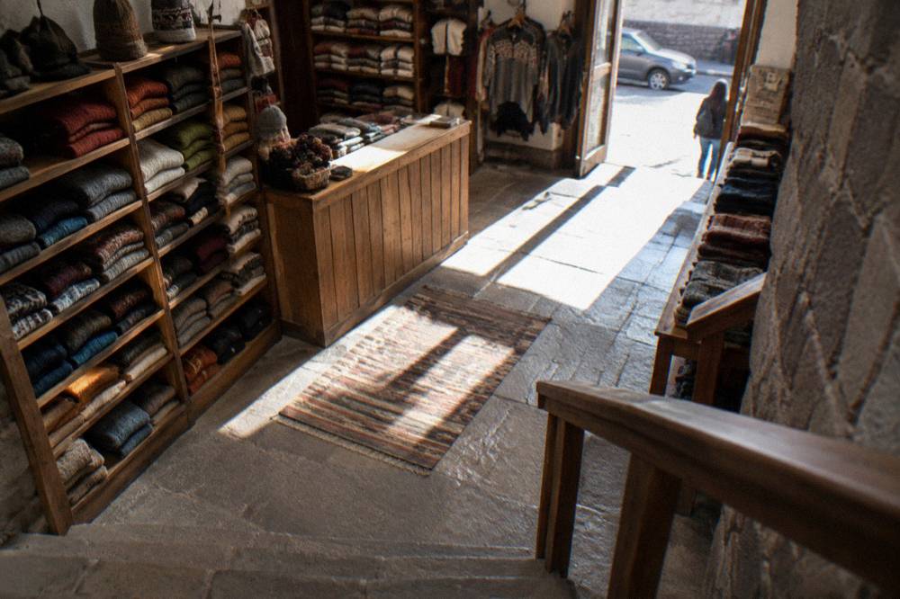 A shop interior in Cusco with folded knitwear shelves and a wooden counter