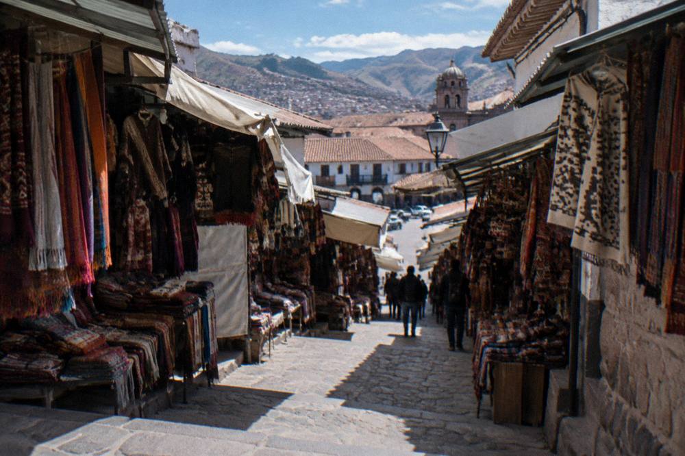 A covered artisan market corridor in Cusco with textile stalls on both sides