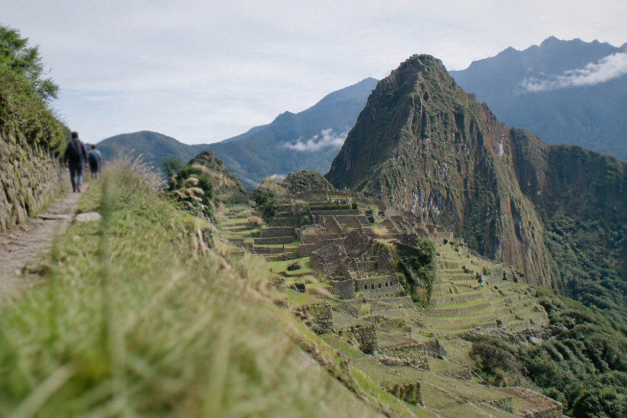 Stone agricultural terraces of a remote Inca site on a green Andean mountainside under a clear sky