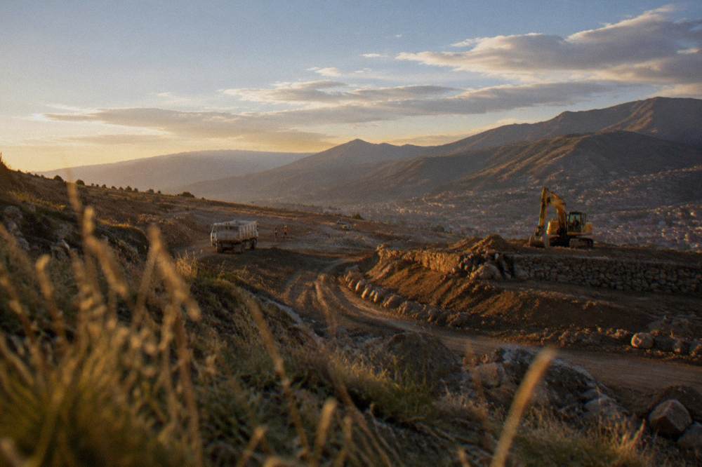 A high plateau construction site with earthworks and mountains under a wide open sky