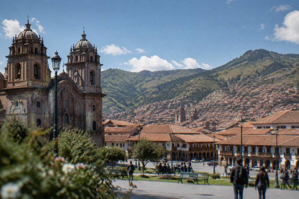 Red tiled roofs of a colonial city spreading across a high valley below green hills