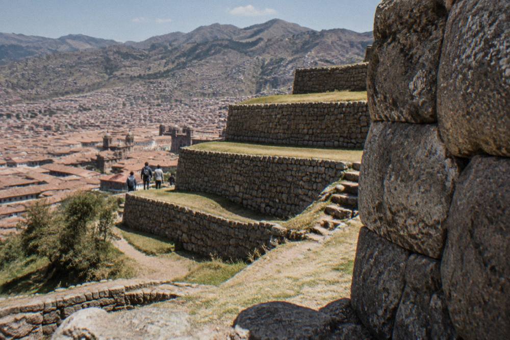 Terraced stone walls of a large Inca archaeological site on a hillside above a city