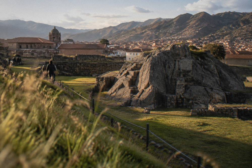 Carved rock outcrop and low stone structures on grassland at an Inca site
