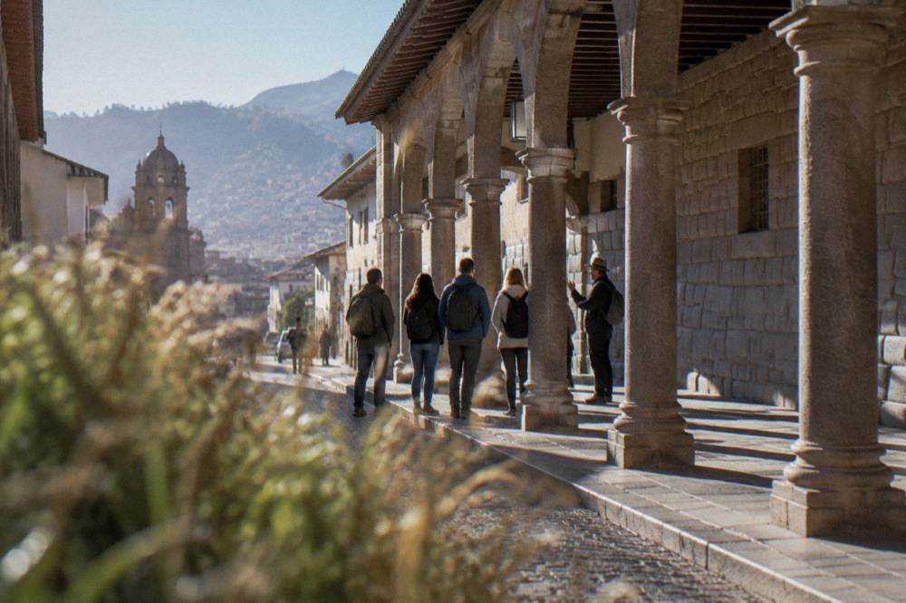 A small group of visitors listening to a guide in a sunlit colonial arcade