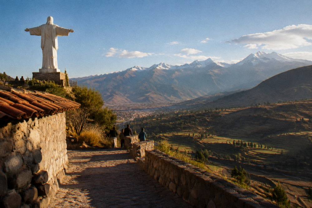 A valley of agricultural terraces and distant snow-capped peaks below a blue sky