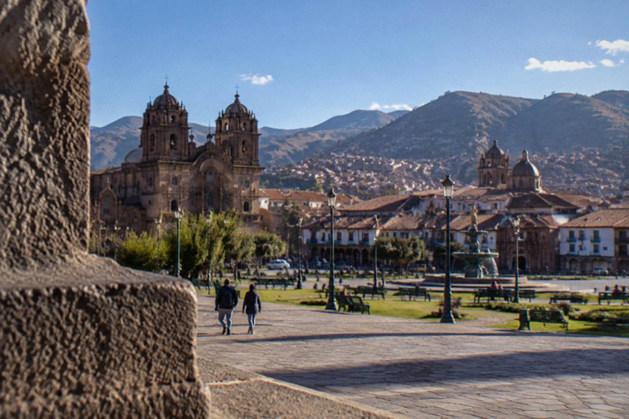 Terracotta rooftops of Cusco with church domes under a bright blue sky