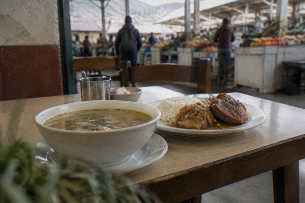 A set lunch of soup, rice and meat on a simple table in a small Cusco eatery
