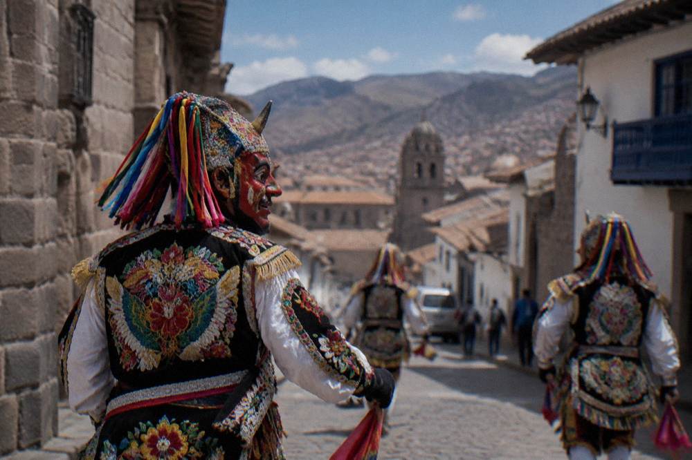 Masked dancers in embroidered costumes in a small Andean town street