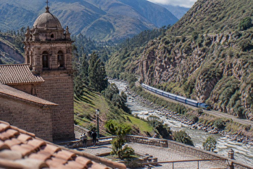 A train winding along a river gorge toward the cloud-forest edge of the Andes