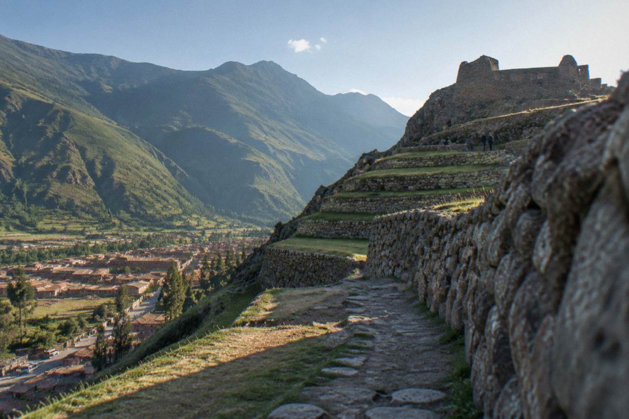 Inca stone terraces of Ollantaytambo rising above the town with green valley hills behind