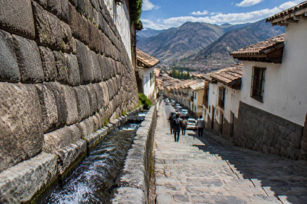 Stone water channel running along an Inca wall in a narrow town street