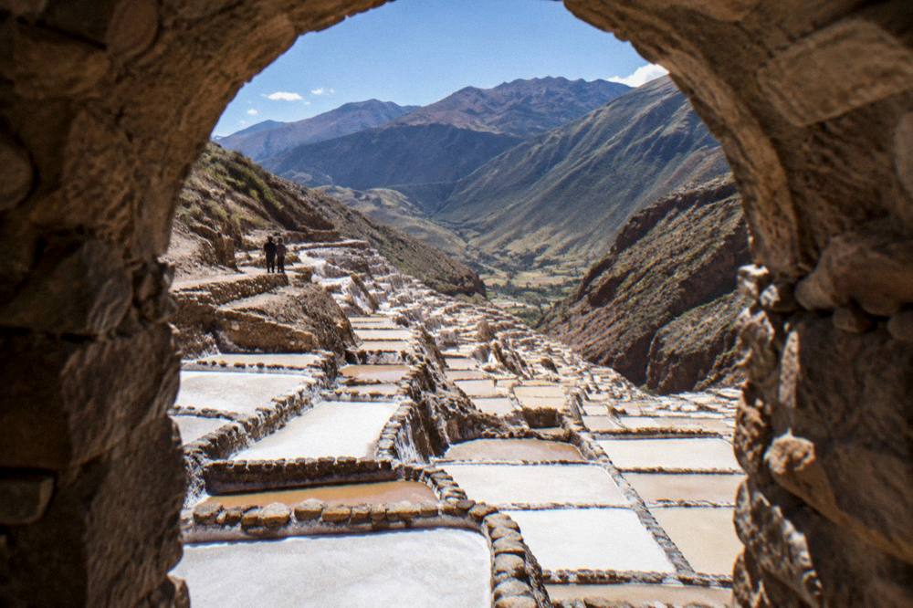 Salt evaporation pans terraced down a hillside in pale shades of cream and brown
