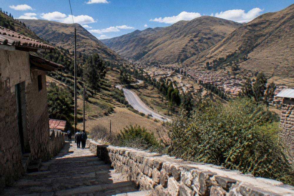Valley road winding between brown Andean hills toward a small town below