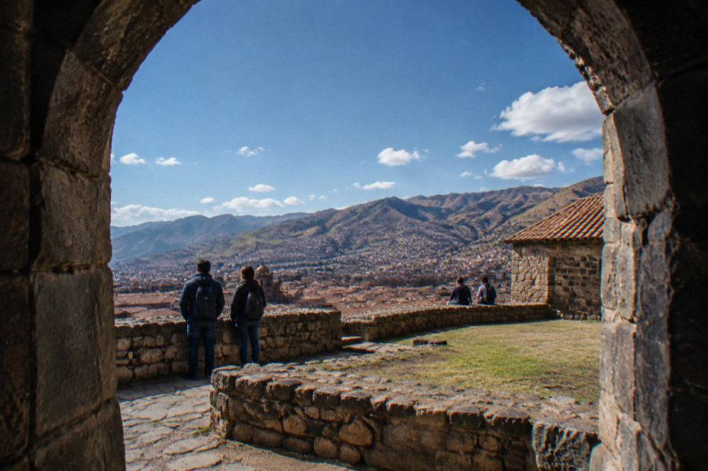 Visitors reading signs outside a stone-walled archaeological site above Cusco