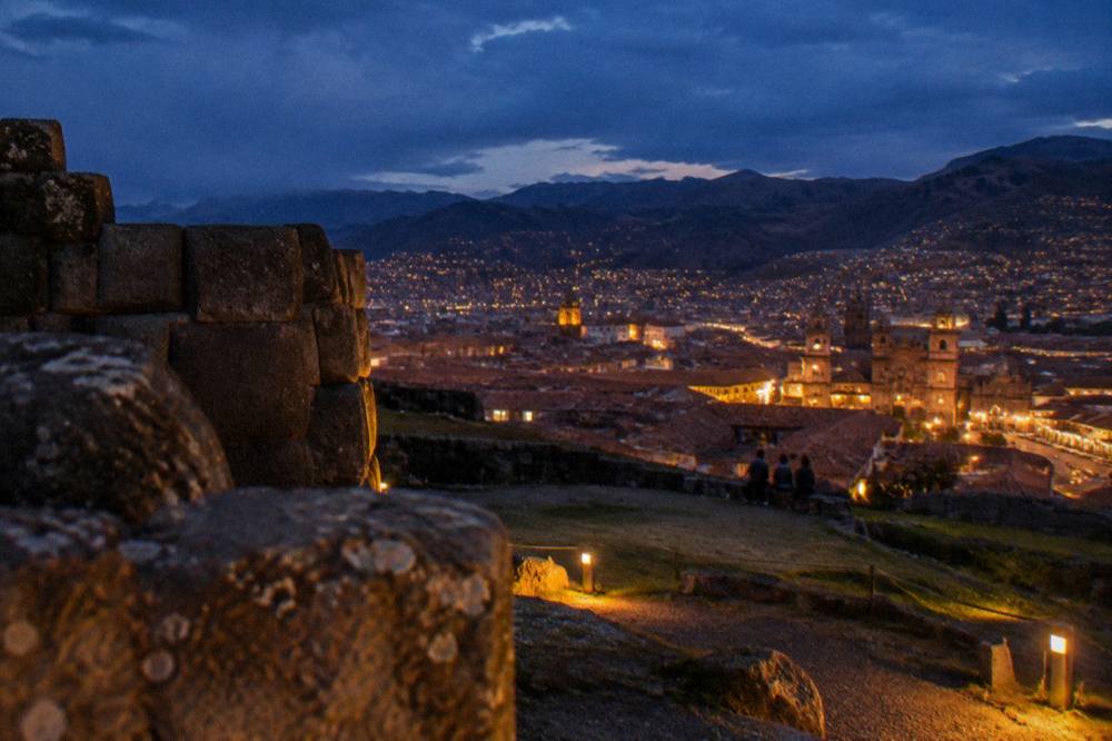 An evening view over Cusco's illuminated rooftops from a hillside lookout
