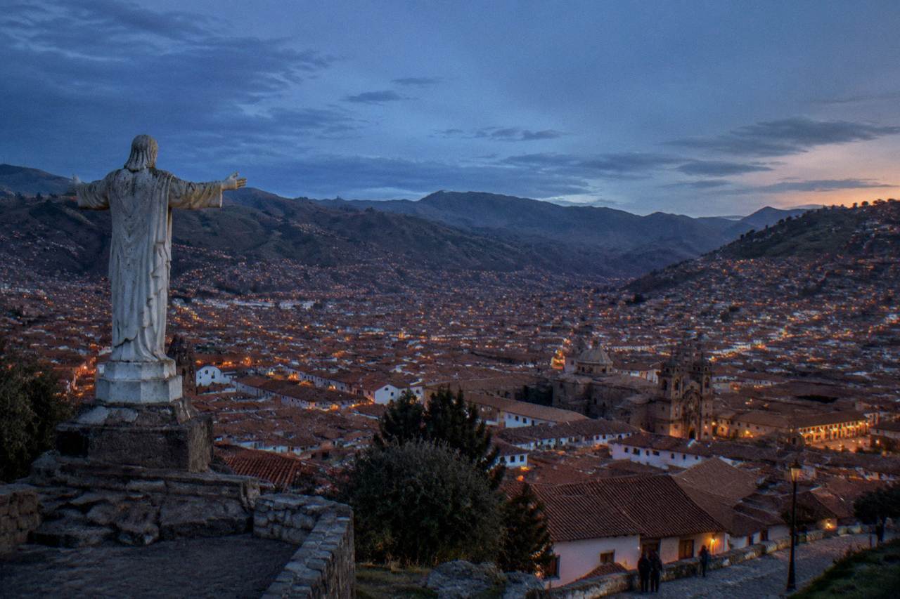 Terracotta rooftops of Cusco under a blue Andean sky with hills rising behind the city