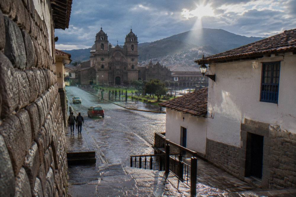 Narrow cobblestone street in Cusco with stone walls in bright morning light