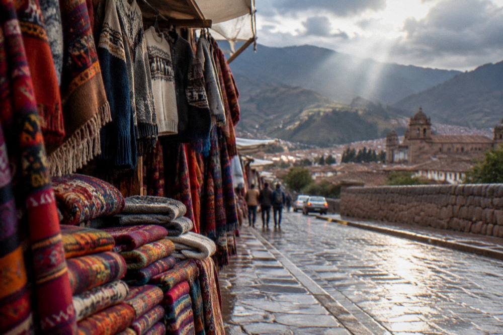 Colourful woven textiles and sweaters displayed on a market stall in Cusco