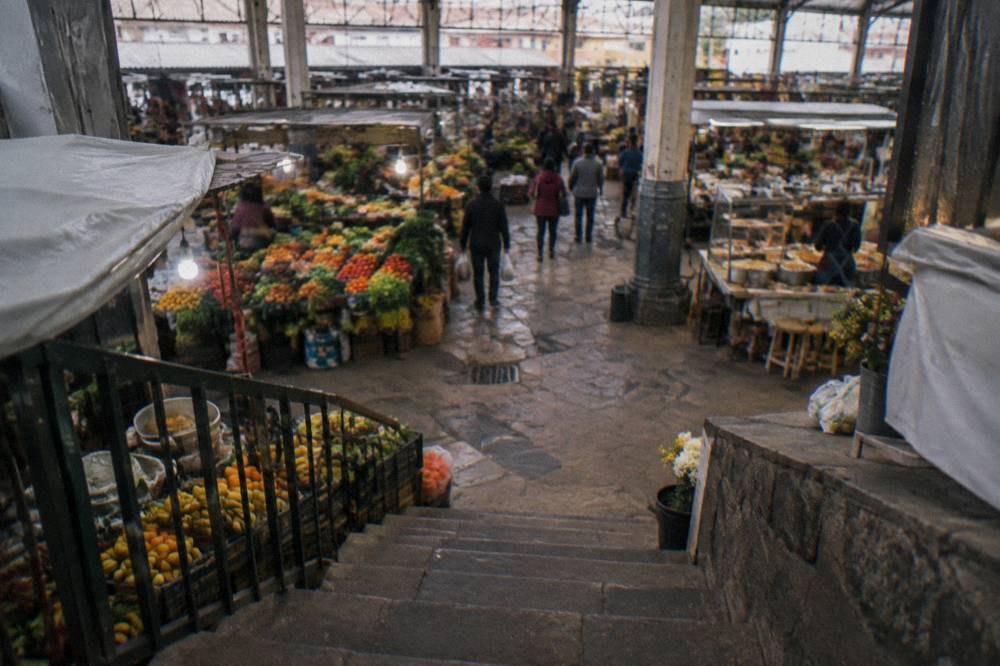 A busy Cusco market hall with stalls of fresh produce and prepared food