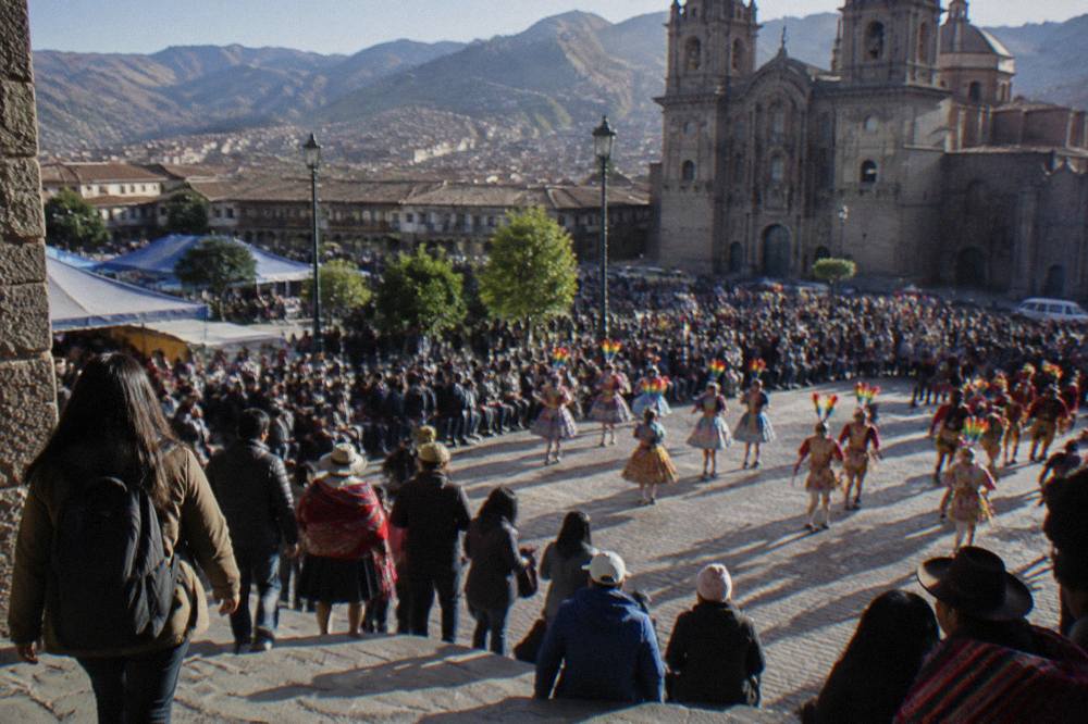 A festival crowd in a Cusco plaza with traditional dancers in costume