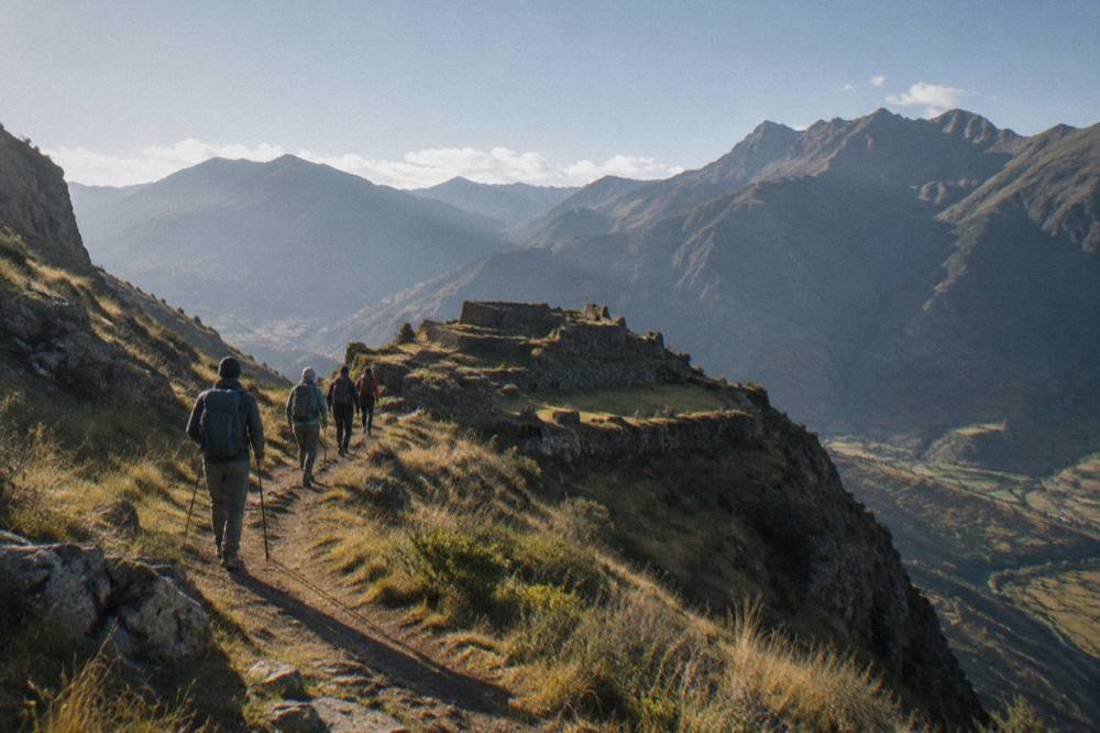 A small trekking group with a guide walking a high ridge trail in morning light